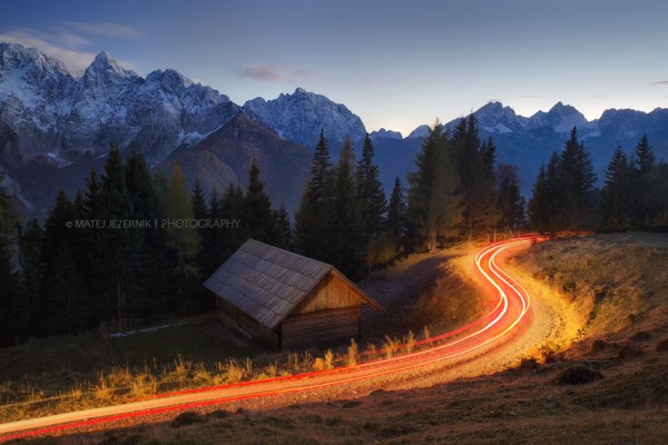 Beautiful autumn day in the Julian Alps area has come to the end. First real snow higher up is just the beginning of the winter season which will follow soon. A cottage and pastures are being lighten up by a car lights, bringing some warmth to the scene. 